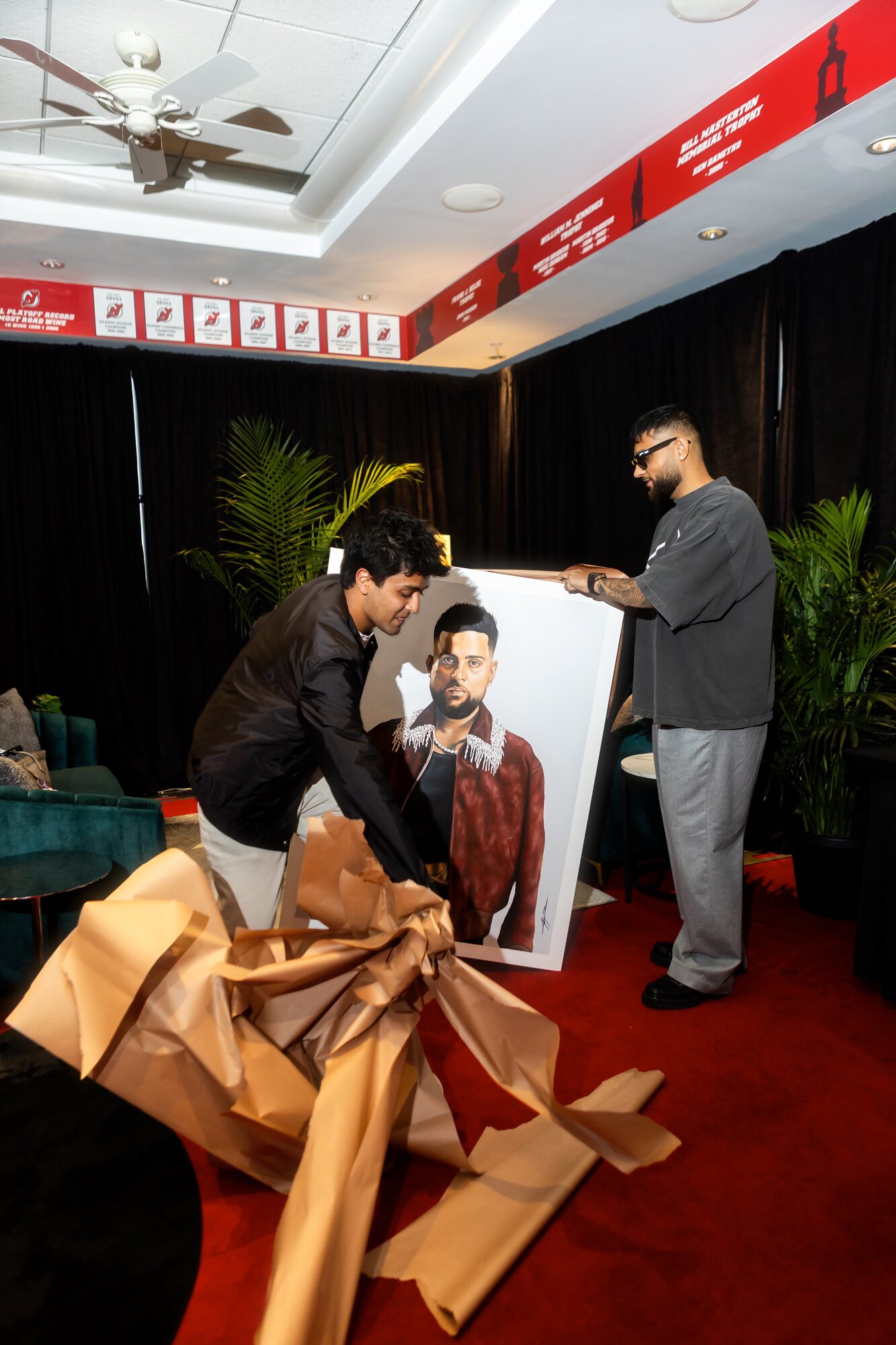 Kyan Patel pulling the wrapping from his portrait of Karan Aujla