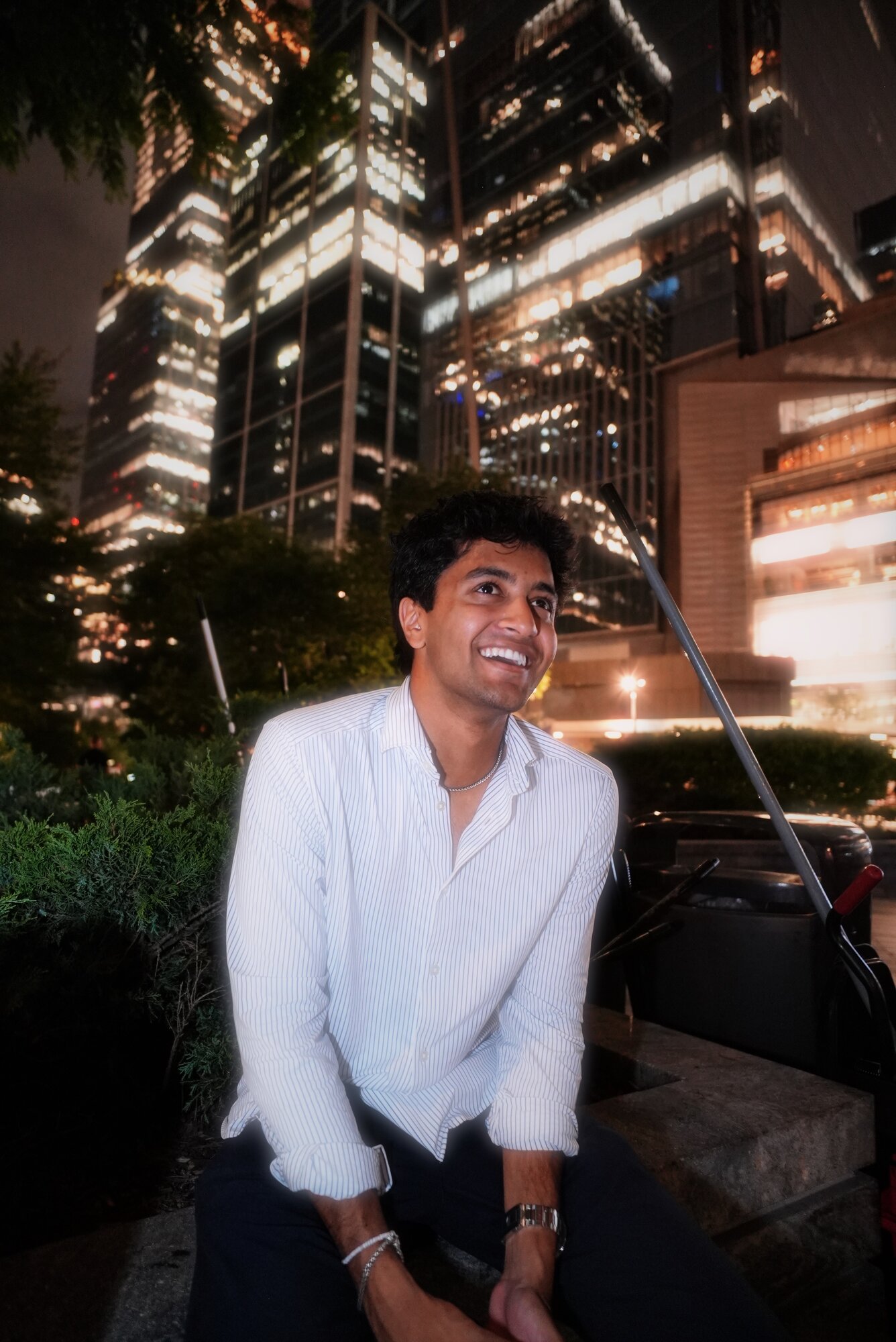Kyan Patel smiling, seated outdoors at night beneath lit city high-rises
