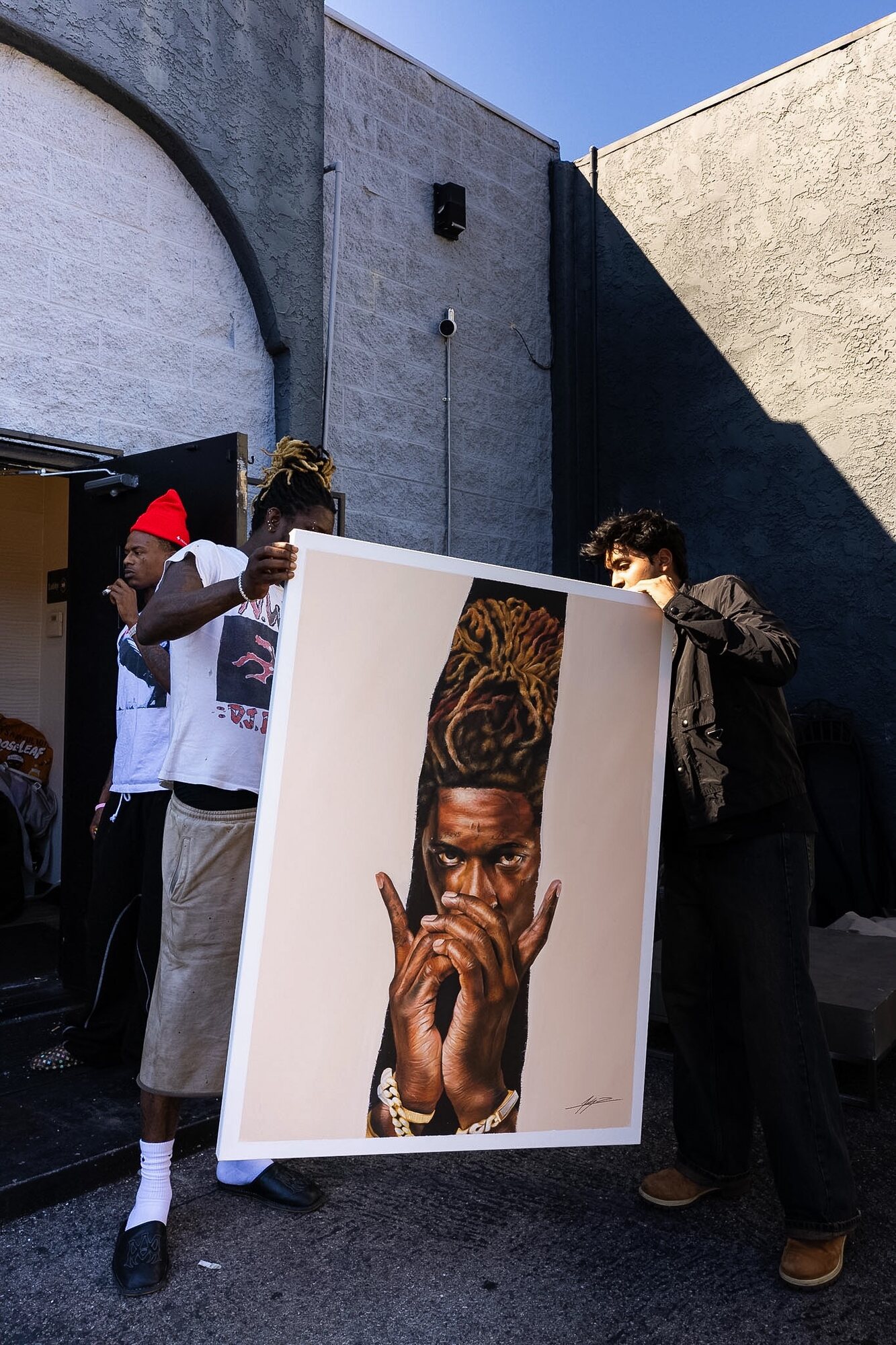 Kyan Patel and Young Thug holding up Kyan’s portrait of the rapper outdoors